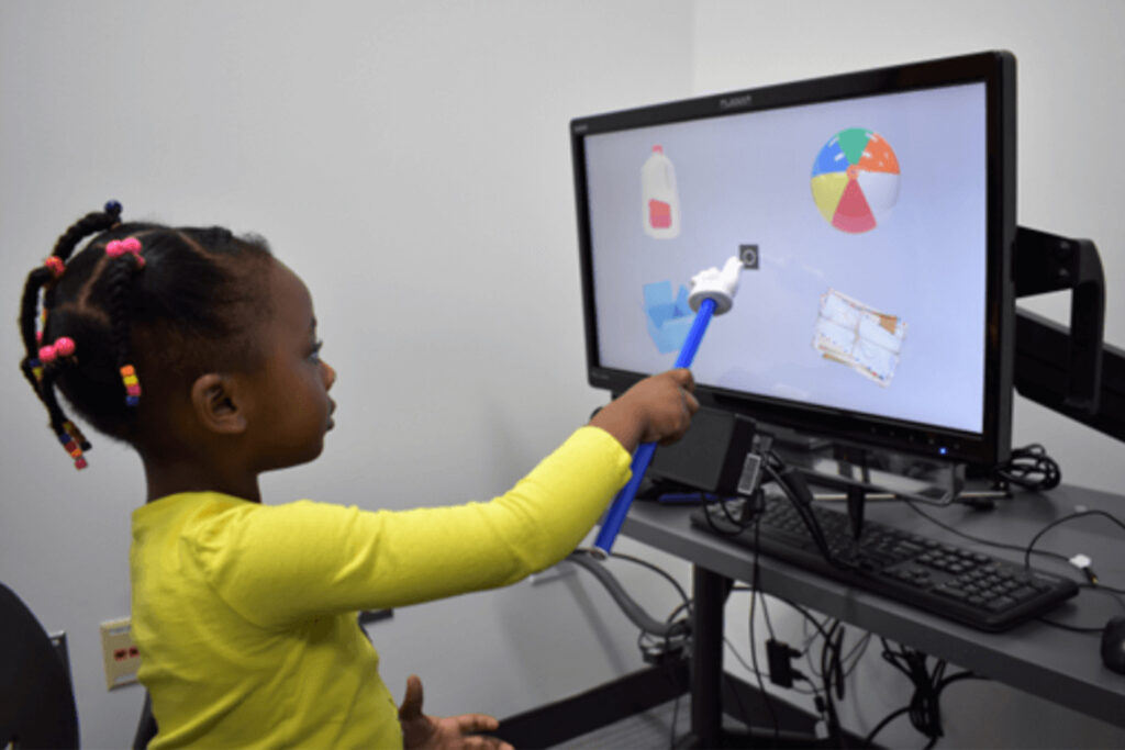 girl pointing at object on the computer